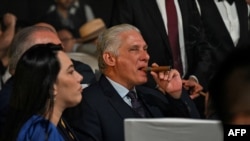 Miguel Díaz-Canel (C) fuma un puro durante una subasta de humidores celebrada como parte de la ceremonia de clausura del XXV Festival del Habano en La Habana, el 28 de febrero de 2025. (Foto de YAMIL LAGE / AFP)